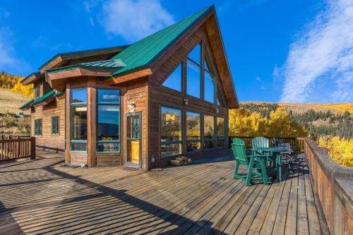 a cabin with a deck with a table and chairs at Above the Clouds in Creede