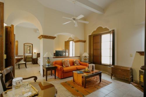 a living room with an orange couch and a table at Hotel Hacienda Los Laureles in Oaxaca City