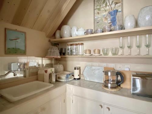a kitchen with a sink and shelves with ceramics at Angel Yard in Woodstock