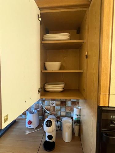 a cupboard with plates and bowls in a kitchen at Champions Deluxe in Sarcelles