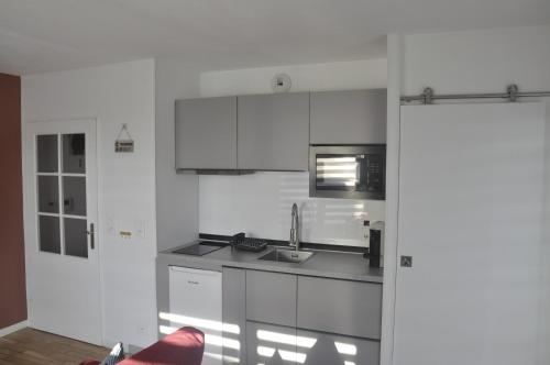 une cuisine blanche avec un évier et un micro-ondes dans l'établissement Pépite Haut De Gamme tous conforts, à Romainville