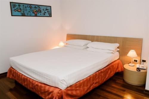 a bedroom with a large bed with white sheets and pillows at Hotel Carlton in Ferrara