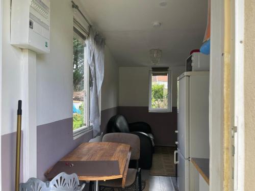 une salle à manger avec une table et un réfrigérateur dans l'établissement Petite maison cosy au fond du jardin, à Belle-Église