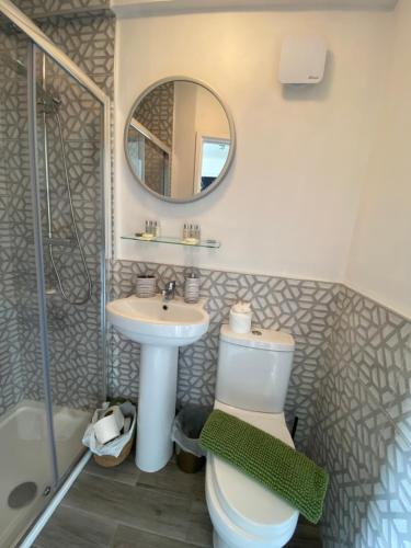 a bathroom with a toilet and a sink and a mirror at The Butterfly Guest House in Porthcawl