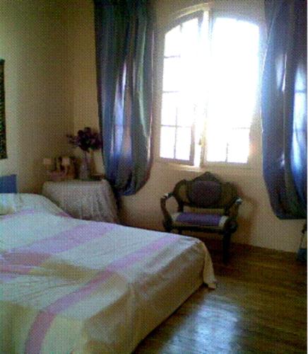 une chambre avec un lit, une chaise et une fenêtre dans l'établissement La Normandie en bord de mer, à Trouville-sur-Mer