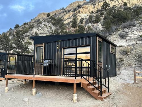 a black tiny house sitting on a wooden platform at Desert Sand in Orderville