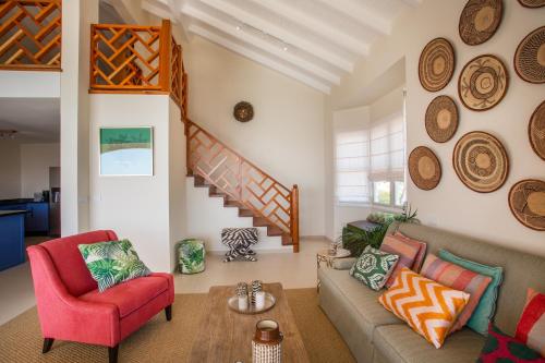 a living room with a couch and a red chair at The Strand - The Beach, Penthouse 4A in Willemstad