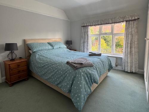 a bedroom with a bed with a blue comforter and a window at Town House, Stratford-upon-Avon in Stratford-upon-Avon