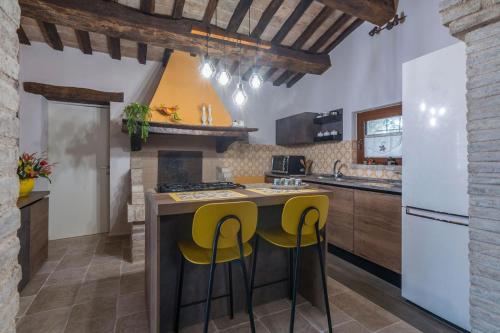 a kitchen with a center island with yellow bar stools at Villa Azzurra in Pesaro