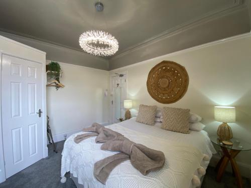 a bedroom with a large white bed with a chandelier at The Butterfly Guest House in Porthcawl