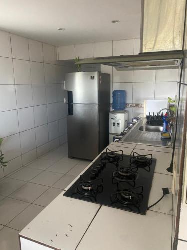 a kitchen with a stove and a stainless steel refrigerator at Linda casa em Enseada dos Corais in Cabo de Santo Agostinho