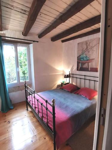 une chambre avec un grand lit avec des oreillers rouges dans l'établissement Maison Marianne et sa Piscine dans le Périgord, à La Bachellerie