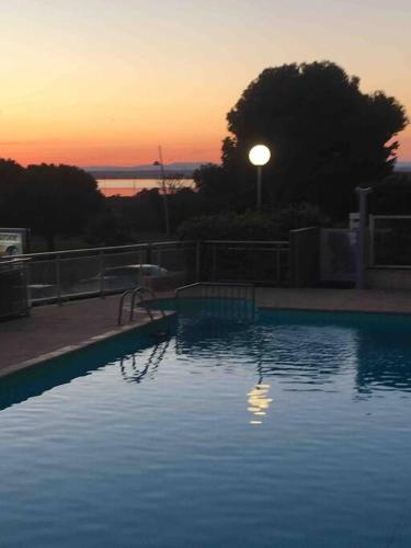 une grande piscine avec un coucher de soleil en arrière-plan dans l'établissement La Mascotte de Sète studio cabine Pking, à Sète