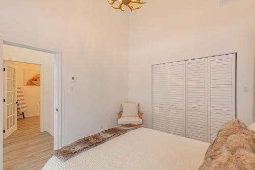 a white bedroom with a bed and a chandelier at Mountain Escape with Pool, Near Ski Slopes & Trails in Wentworth-Nord