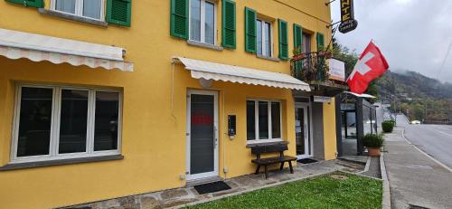 a yellow building with green windows and a flag at Hotel Elvezia - Self Check-in in Lavorgo