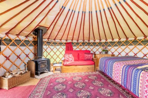 a room with a bed and a stove in a yurt at Cosy-Hilltop-Yurt-StunningViews-Nature-HotTub in Cornworthy