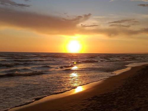 a sunset on a beach with the ocean at La Maisonette di Eliana - free parking in Passoscuro
