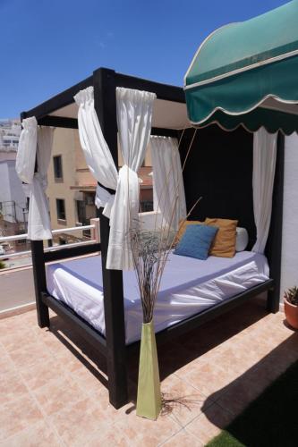 a bedroom with a canopy bed and a vase with flowers at Viviendas Vacacionales Marcial in Morro del Jable