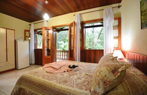 a bedroom with a bed in a room with windows at Chalés Caminho das Montanhas in Monte Verde