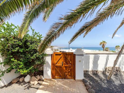 a wooden door on a white wall with a beach at Casa Susanne in Famara