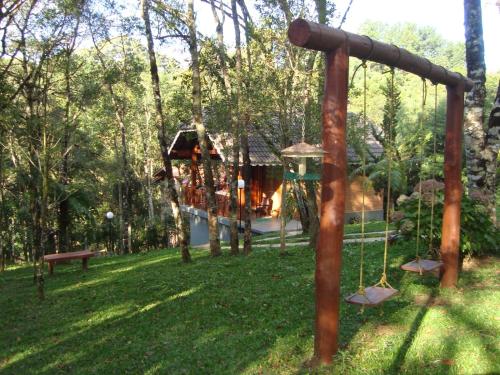 a playground in a park with a swing at Chalés Caminho das Montanhas in Monte Verde