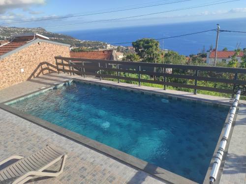 a swimming pool with a bench and the ocean in the background at Villa do Italiane in Estreito da Calheta