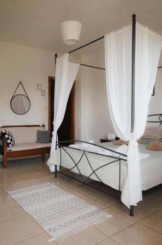 a bedroom with a canopy bed with white curtains at Lefteris Rooms in Kámbos