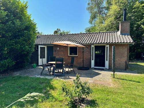 a small house with a table and chairs and an umbrella at Achterhoekhuisje De Rode Beuk in Hummelo