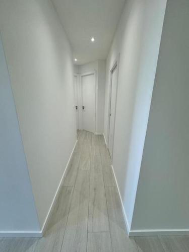 un couloir vide avec des murs blancs et du parquet dans l'établissement Appartement meublé de 120 m2, à Coudun