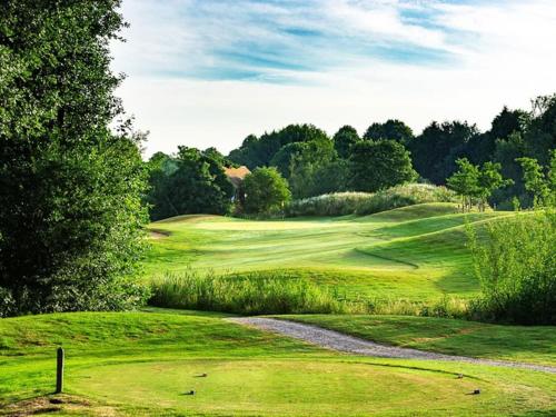 a green golf course with a road leading up to it at 2BDR Cottage By Guest Nest Management In Horsham With Free Parking in Horsham