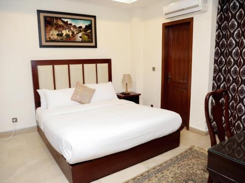 a bedroom with a white bed and a wooden door at Executive Residency in Islamabad
