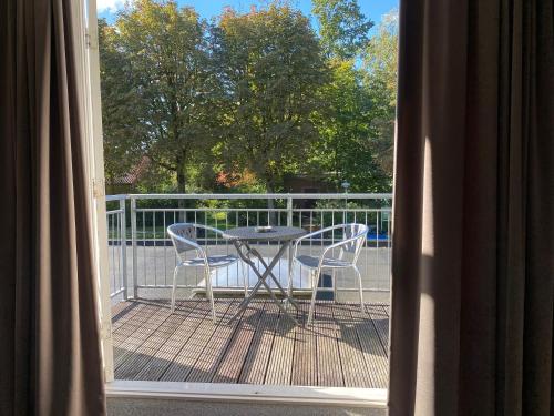 a balcony with a table and chairs on a deck at Hotel and Restaurant van Saaze in Kraggenburg