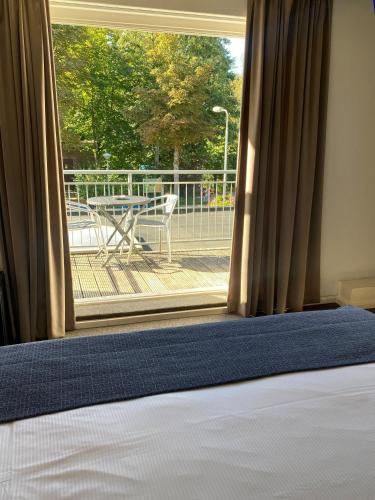 a room with a bed and a window with a table at Hotel and Restaurant van Saaze in Kraggenburg