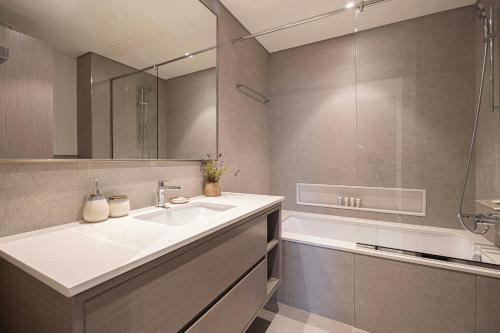 a bathroom with a sink and a tub and a mirror at Best View In Dubai With FULL Burj Khalifa, Fountains, Park View, Next to Dubai Mall and Opera in Dubai
