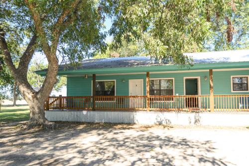 a green house with a porch and a tree at Turn On Inn in Lake Village