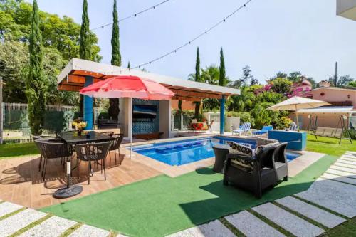 a patio with a table and umbrella and a pool at Mini Casita, around nature in Santa Cruz de la Soledad
