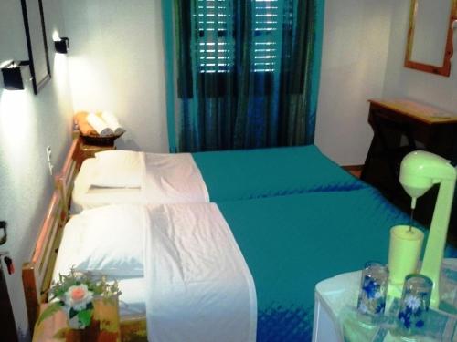a bedroom with a bed with a blue blanket and a table at skiathosrooms-appartments for holidays in Skiathos Town