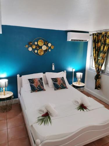 a bedroom with a white bed with a blue wall at Les Gîtes de la Lézarde in Petit-Bourg