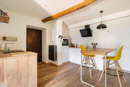 une cuisine avec une table en bois et des tabourets de bar jaunes dans l'établissement Citadelle de Bastia - duplex - vue mer, à Bastia