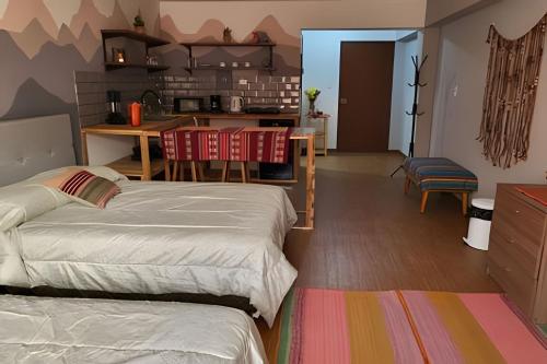 a room with two beds and a table and a kitchen at Alojamiento San Francisco - Apartamentos y habitaciones in Lima
