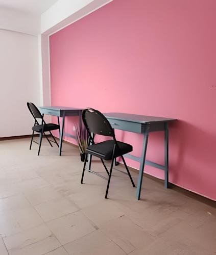 a table with two chairs and a pink wall at Alojamiento San Francisco - Apartamentos y habitaciones in Lima