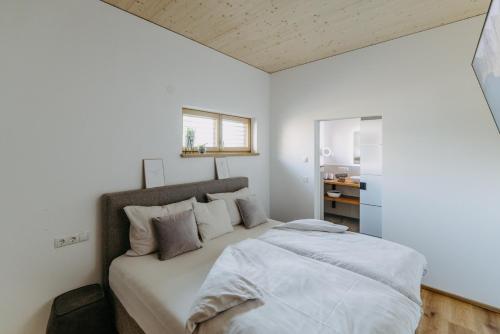 a bedroom with a bed with white sheets and a window at Ferienhaus LuckyLiving in Litzelsdorf