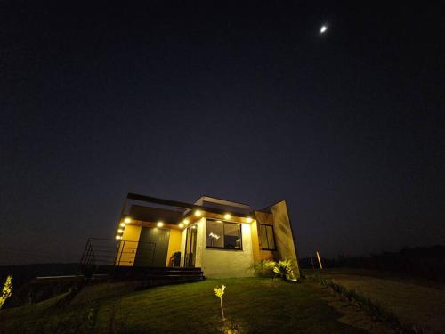 a small house with lights on the side of it at night at Solarium Mantiqueira 2 - Cinema e vistas incríveis in Itanhandu