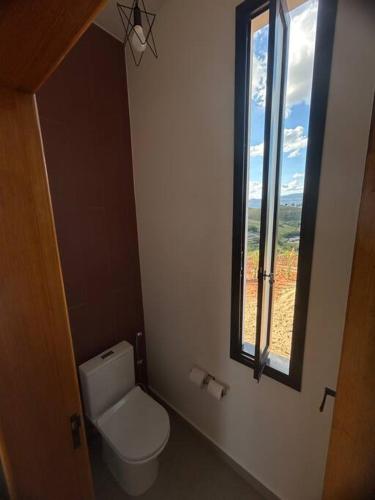 a bathroom with a toilet and a window at Solarium Mantiqueira 2 - Cinema e vistas incríveis in Itanhandu