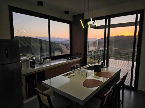 a kitchen with a table with chairs and a large window at Solarium Mantiqueira 2 - Cinema e vistas incríveis in Itanhandu