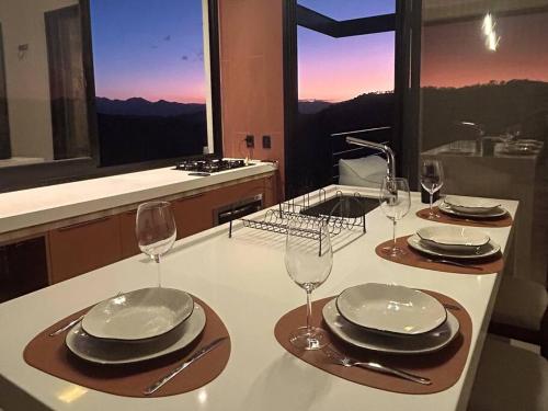 a table with plates and wine glasses on a counter at Solarium Mantiqueira 2 - Cinema e vistas incríveis in Itanhandu