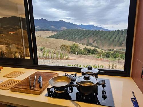 a stove with two pots and pans on a counter next to a window at Solarium Mantiqueira 2 - Cinema e vistas incríveis in Itanhandu
