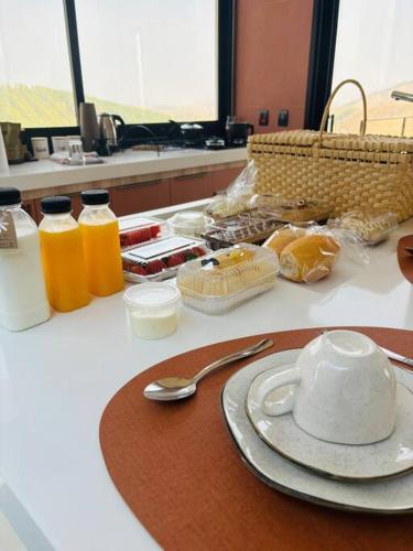 a table with a plate of food and bottles of orange juice at Solarium Mantiqueira 2 - Cinema e vistas incríveis in Itanhandu