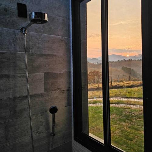 a shower in a bathroom with a window at Solarium Mantiqueira 2 - Cinema e vistas incríveis in Itanhandu
