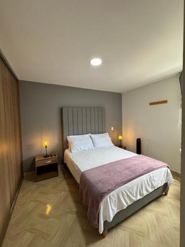 a bedroom with a large bed and two lamps on a table at Piso13 Sabaneta, apartment, Parking, Pool & with club in the sky! in Sabaneta